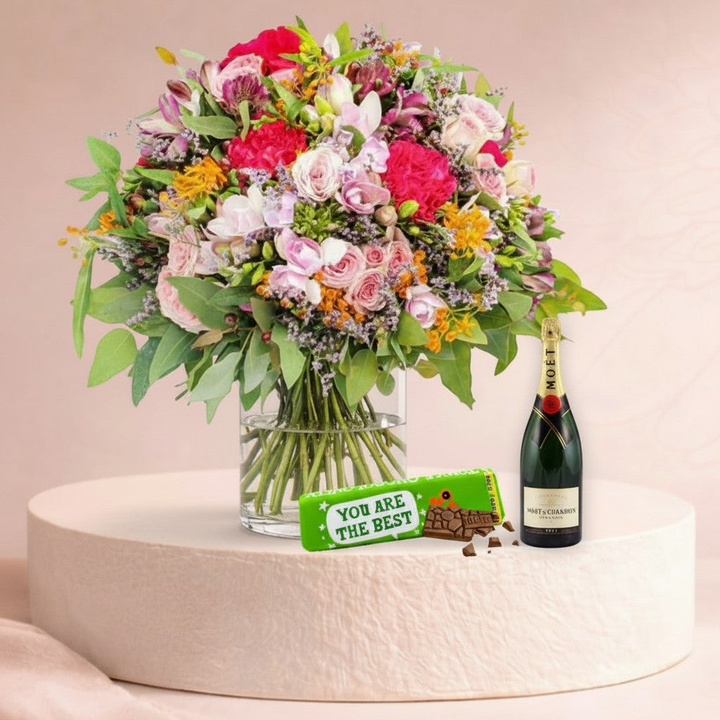 Flower Station joyful bouquet with pink dianthus, spray roses, alstroemerias, Moët & Chandon champagne, and Tony's Chocolonely dark chocolate.